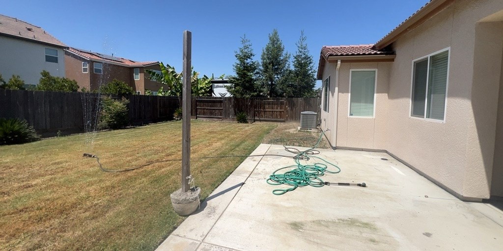 the backyard of a house with a hose on the ground