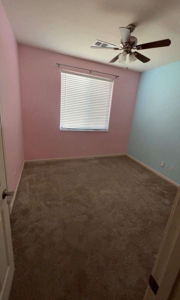 an empty room with a ceiling fan and a window