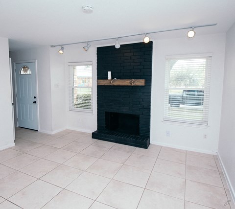 an empty living room with a black brick fireplace