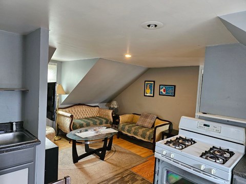 A living room with a couch, chairs, and a stove.