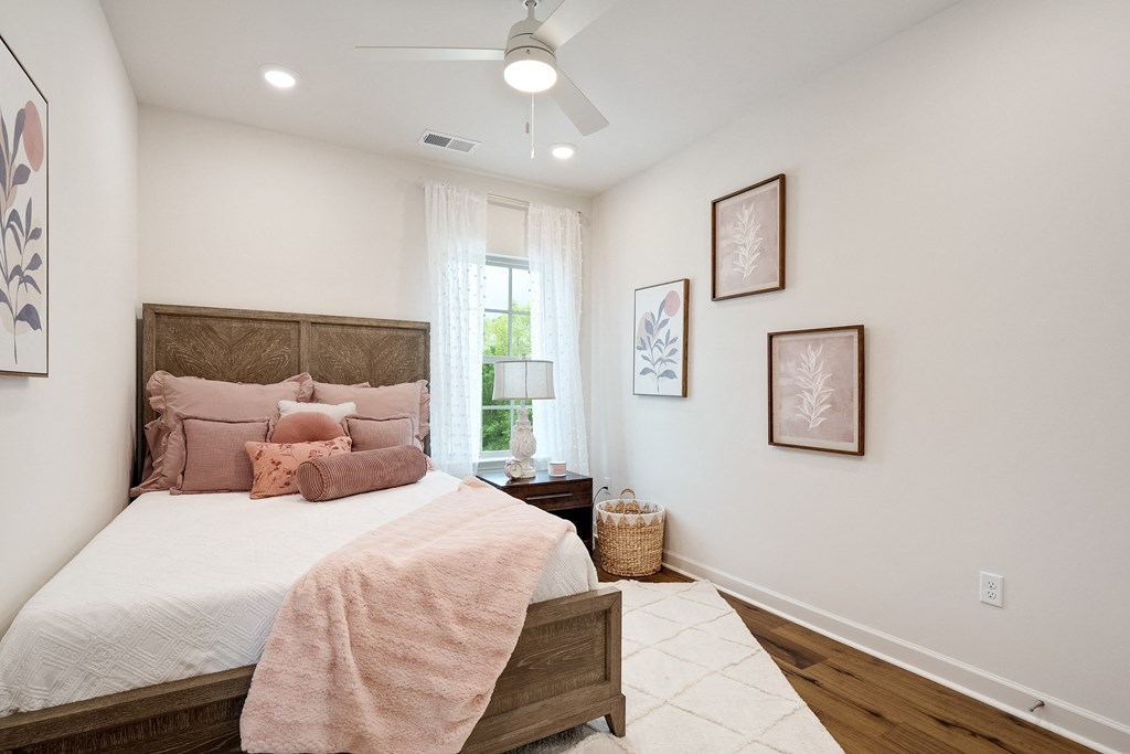 a bedroom with white walls and a bed with pink pillows