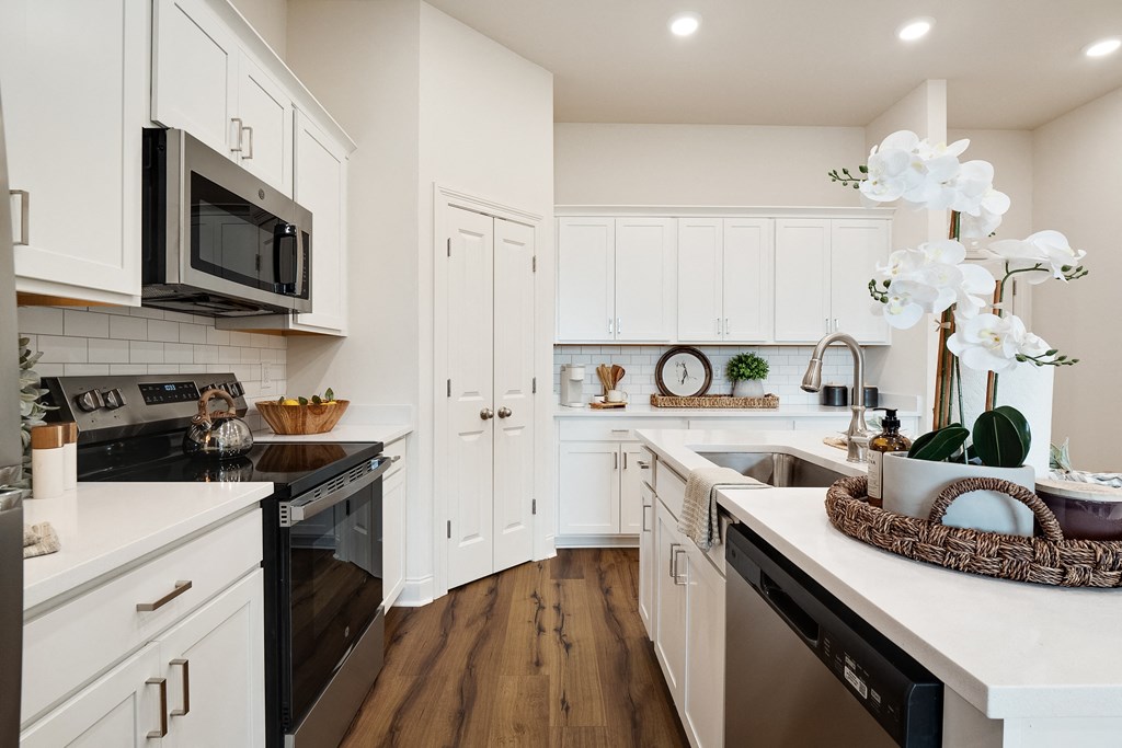 a white kitchen with stainless steel appliances and white cabinets