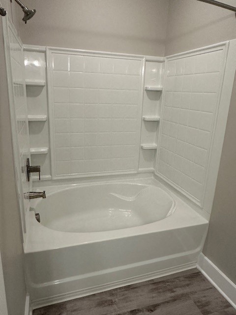 a small white bathroom with a tub and shelves