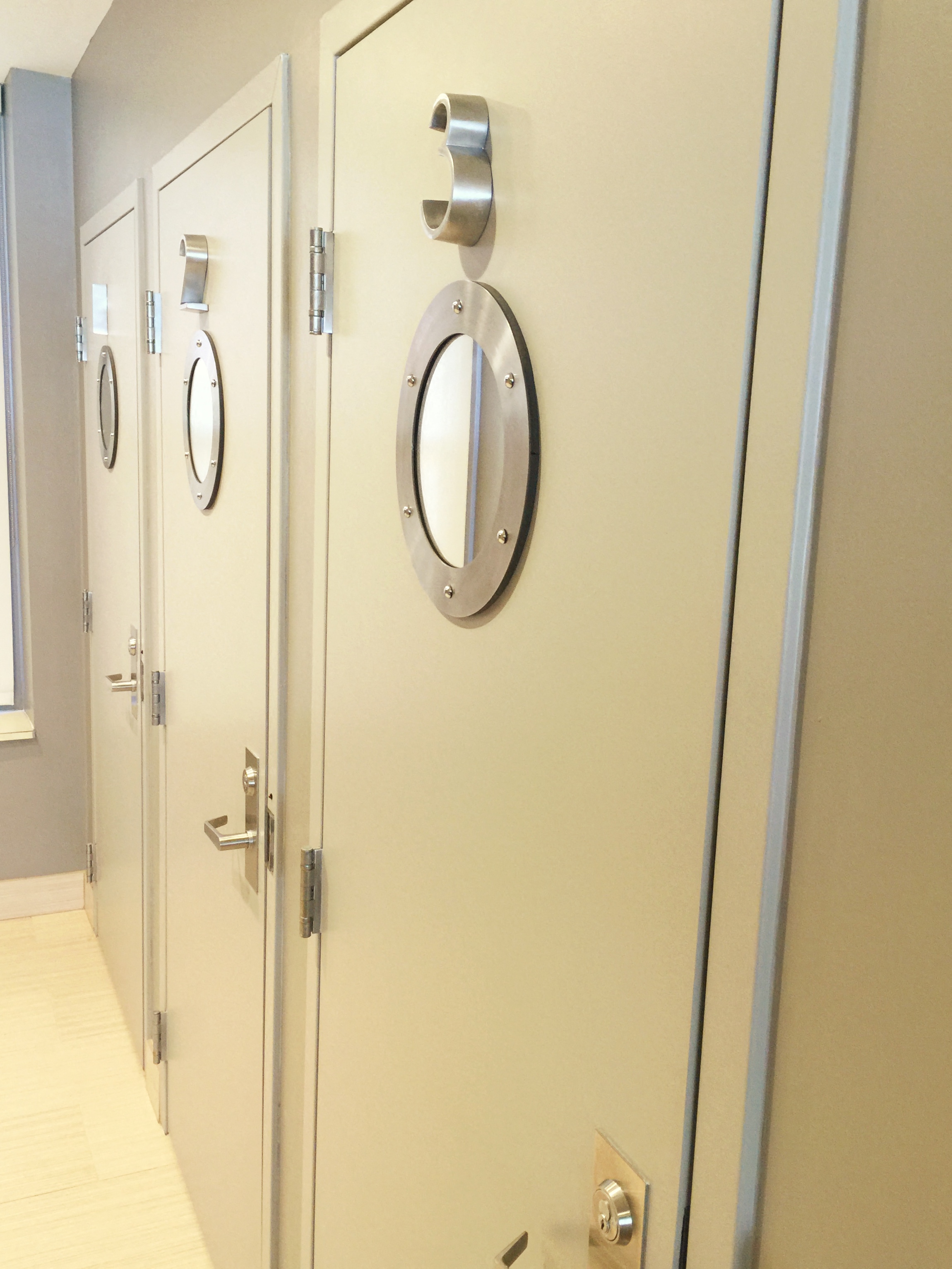 a row of bathroom doors with round mirrors on them