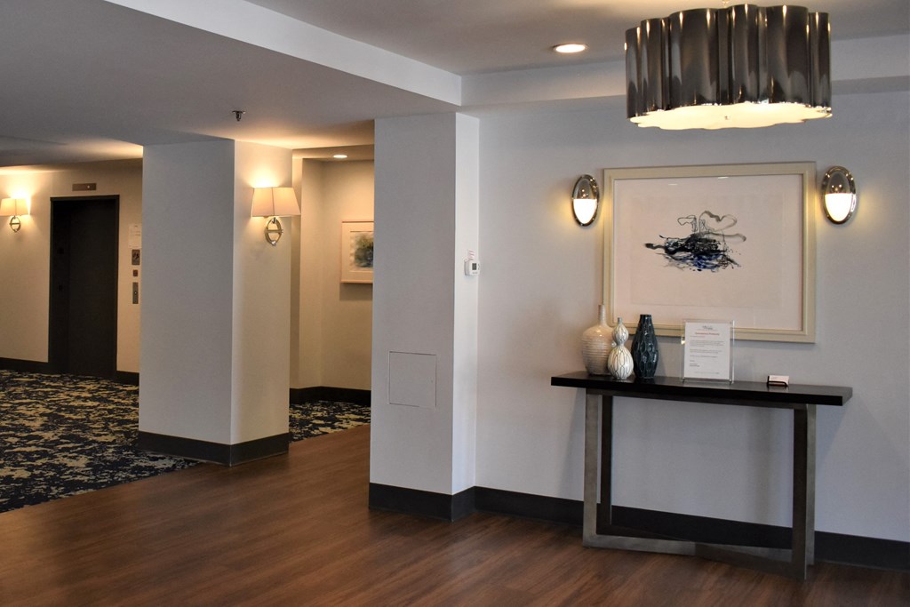 a lobby with a table and a painting and a hallway with a door