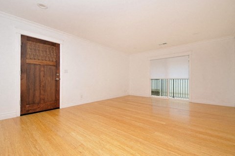 an empty living room with wooden floors and a wooden door