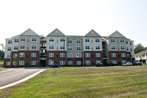 the exterior of an apartment building with cars parked in front