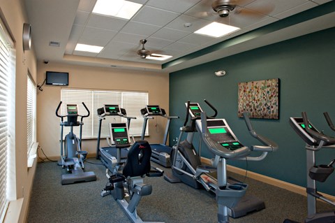 a gym with four exercise machines and a tv