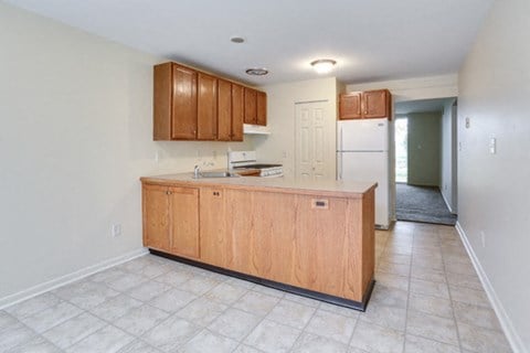 an empty kitchen with wooden cabinets and a refrigerator