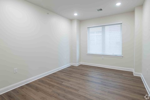 a living room with white walls and wooden floors and a window