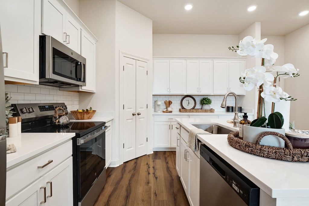 a white kitchen with stainless steel appliances and white cabinets