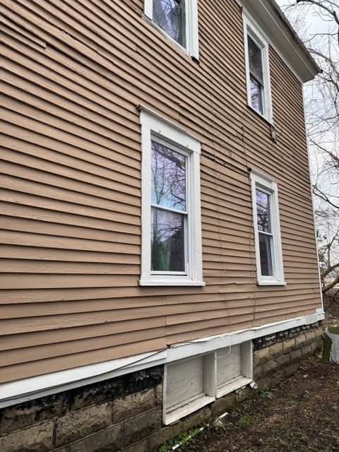 the side of a house with brown siding and white windows