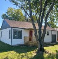 a small white house with a tree in front of it