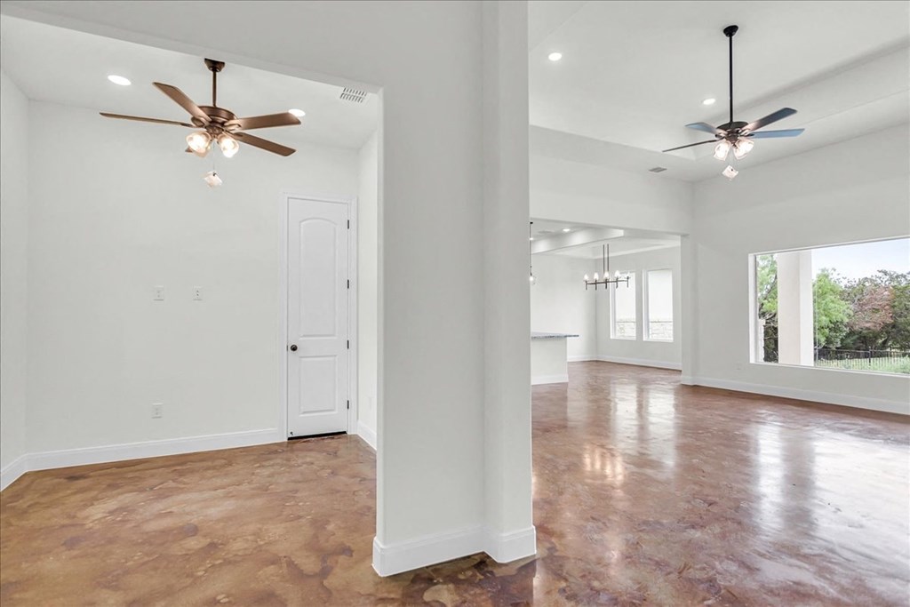 an empty living room and kitchen with two ceiling fans