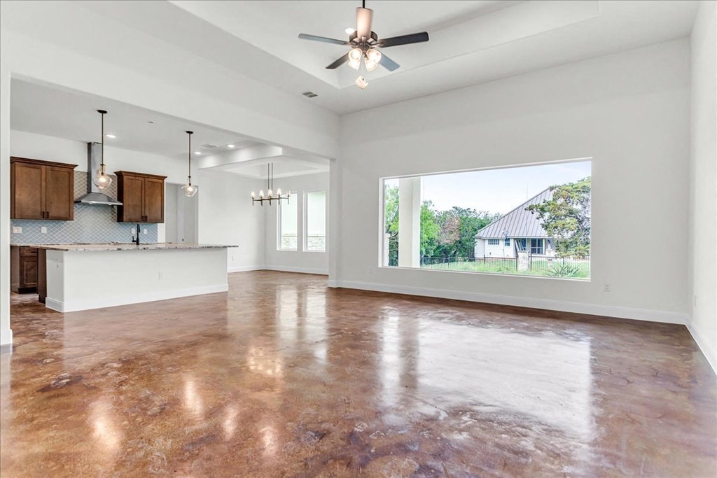 an empty living room with a large window and a kitchen