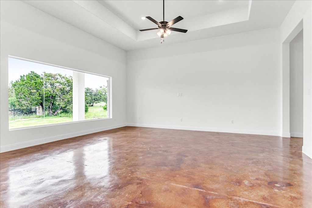an empty living room with a large window and a ceiling fan