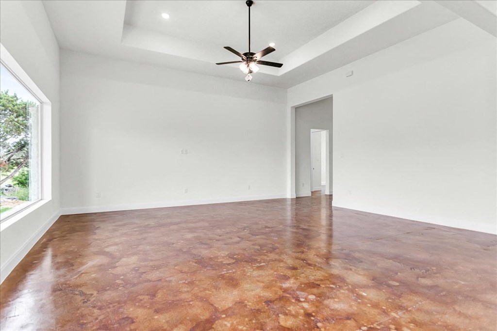 an empty living room with a ceiling fan and a window