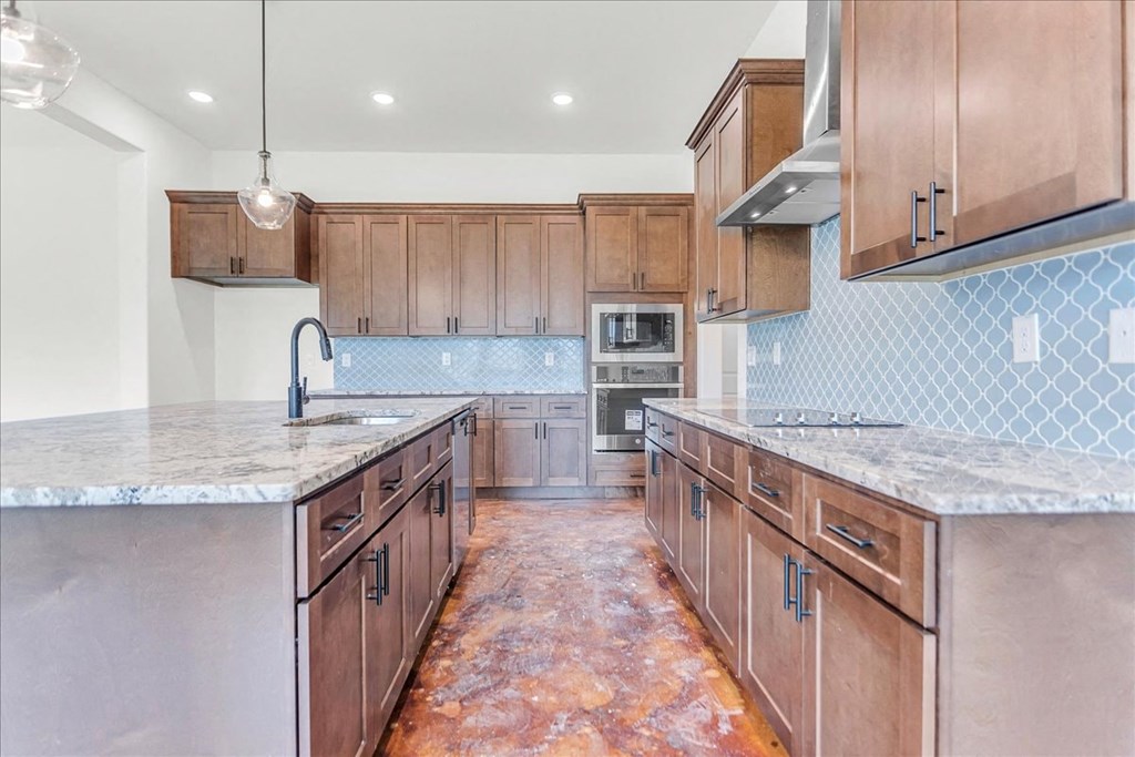 a large kitchen with wooden cabinets and marble counter tops