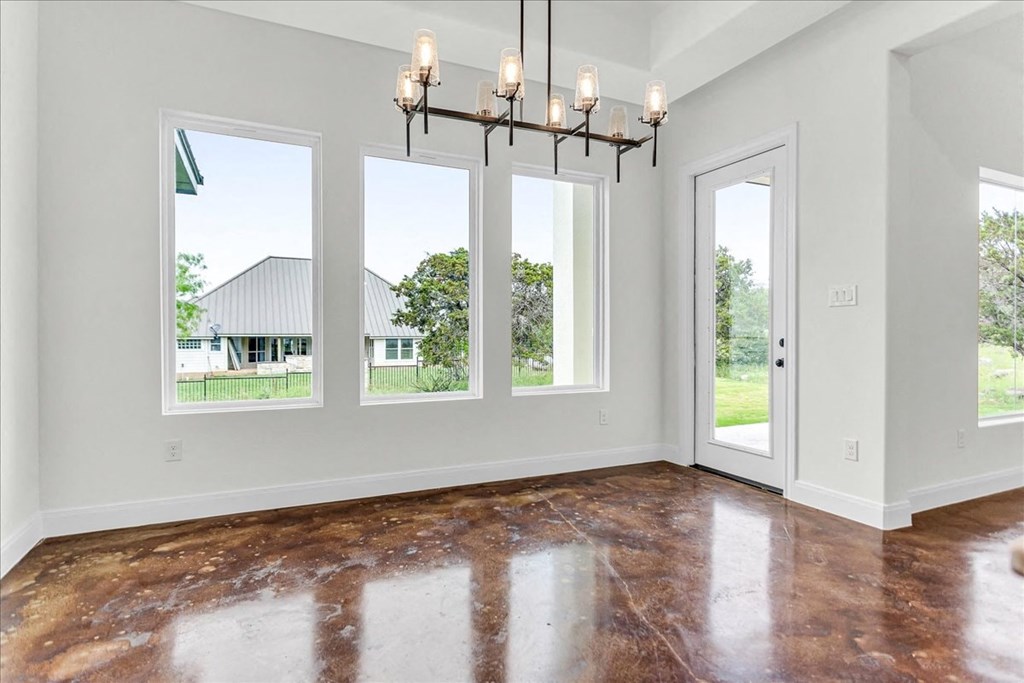 an empty living room with three windows and a chandelier