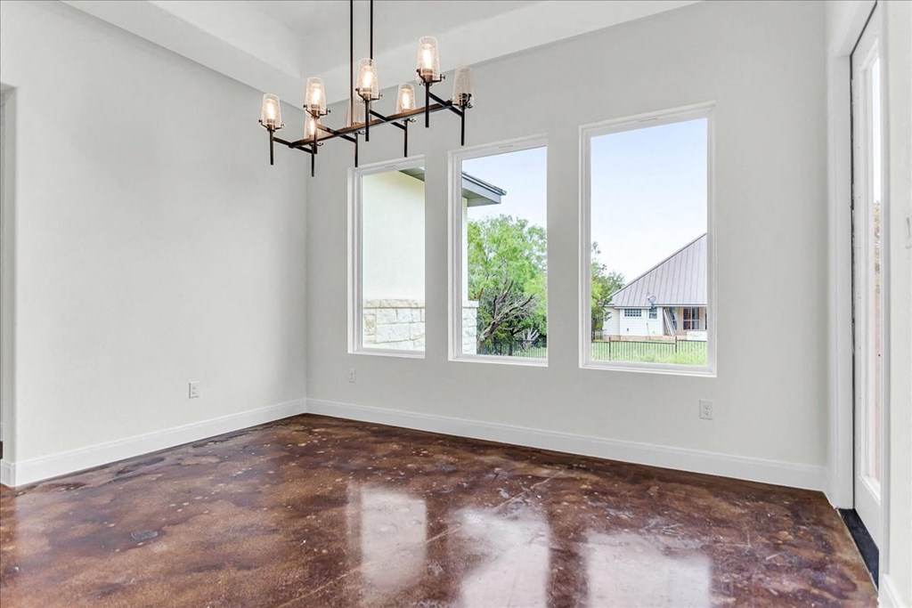an empty living room with three windows and a chandelier