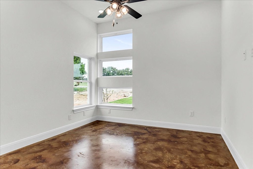 an empty living room with a window and a ceiling fan