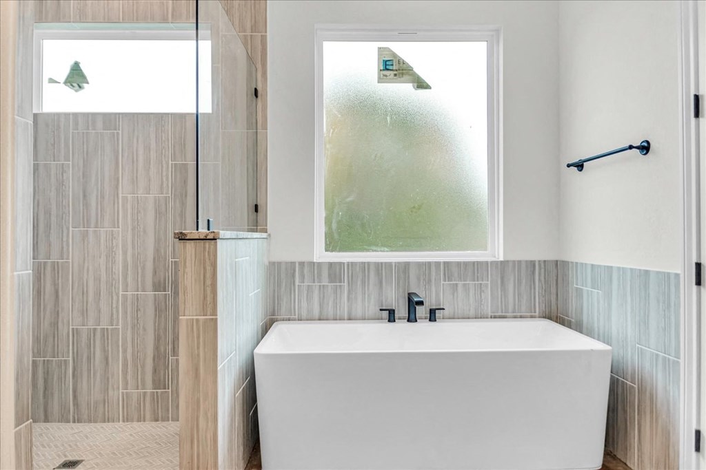 a white bath tub sitting under a window in a bathroom
