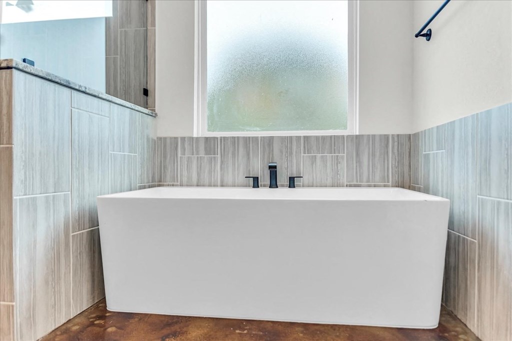 a white bath tub sitting under a window in a bathroom