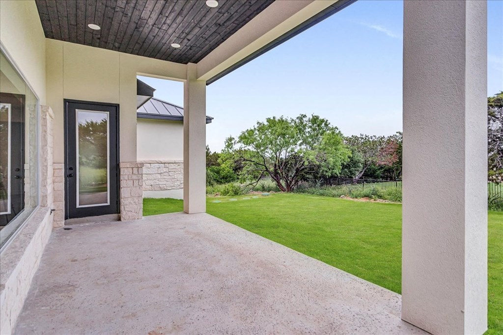 a covered patio with a lawn and a door to a house