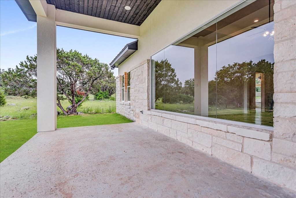 the patio of the house has a large window and a concrete floor