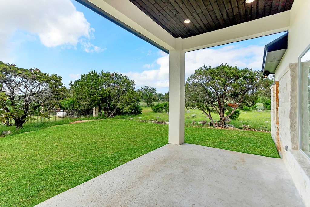 a concrete porch with a view of grass and trees