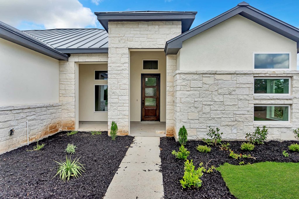 the front of a house with stone walls and a sidewalk
