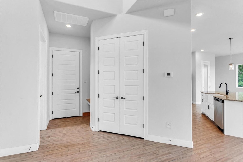 a white kitchen with two white closets and a wooden floor