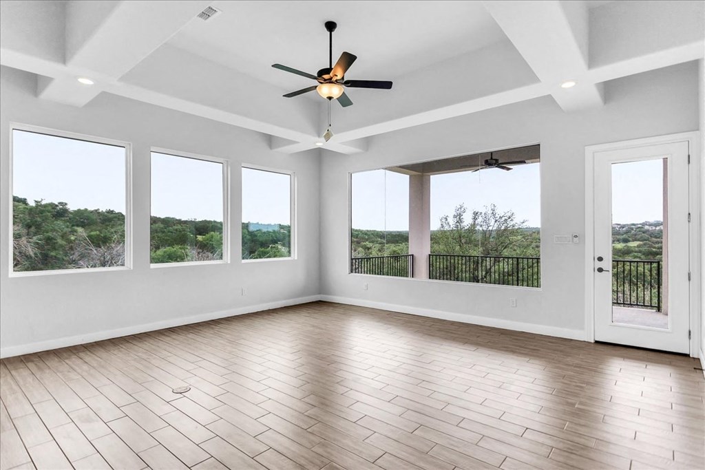 an empty living room with a ceiling fan and windows
