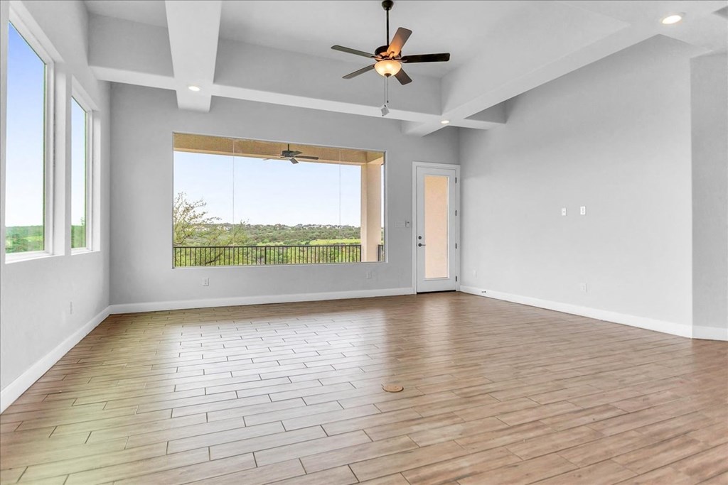 an empty living room with a large window and a ceiling fan