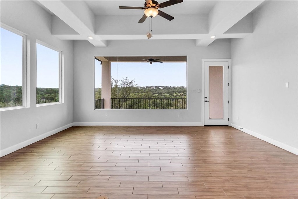 an empty living room with a ceiling fan and a window
