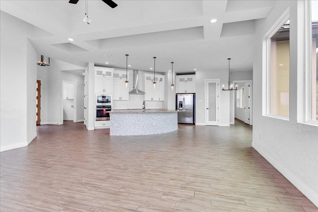 an open kitchen and living room with white walls and wood floors