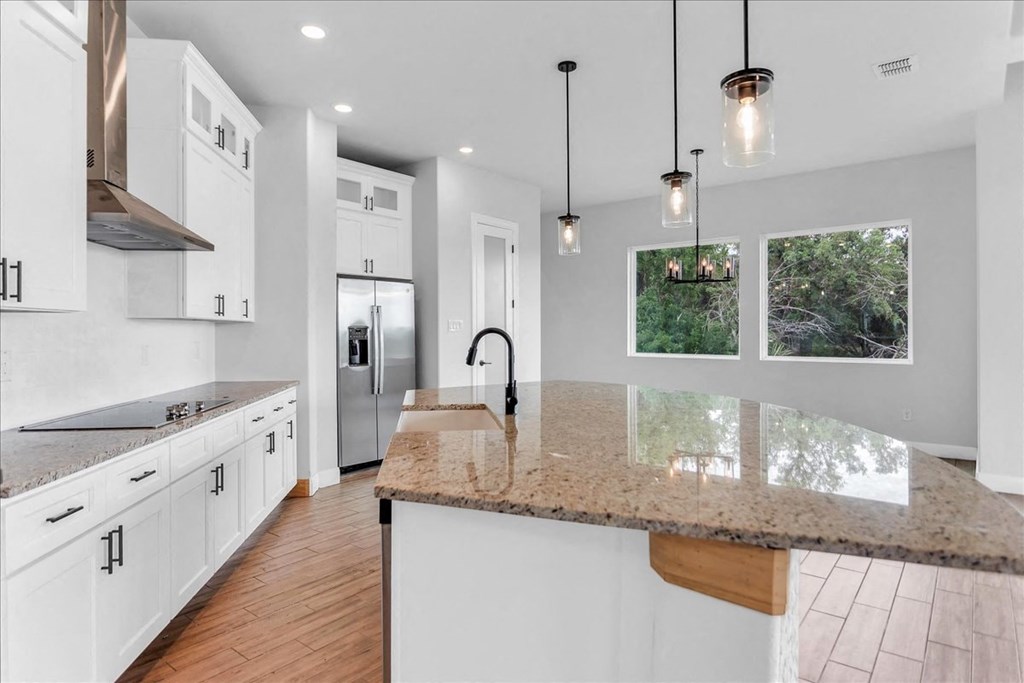 the kitchen has a large island with granite counter tops and white cabinets