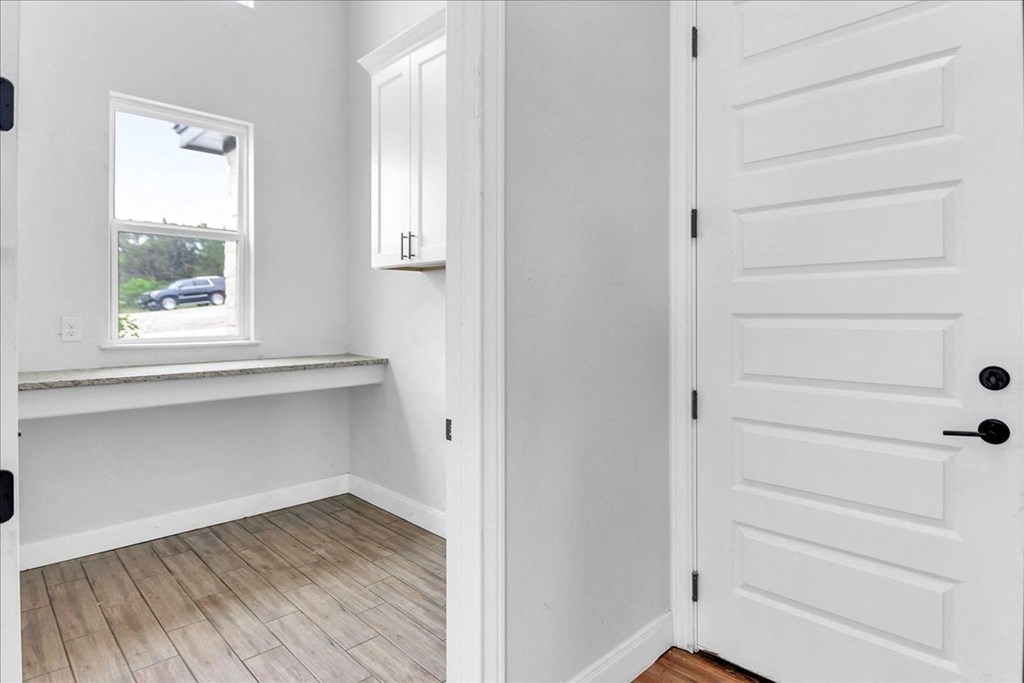 a room with a desk and a window and a white door