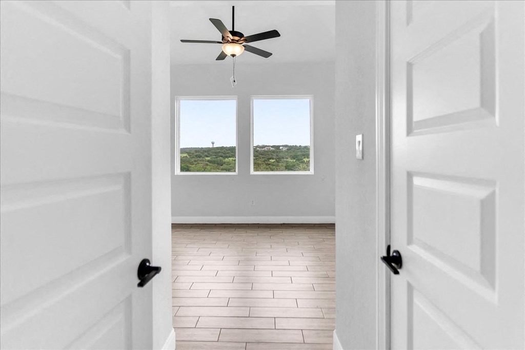 an empty living room with white walls and a ceiling fan