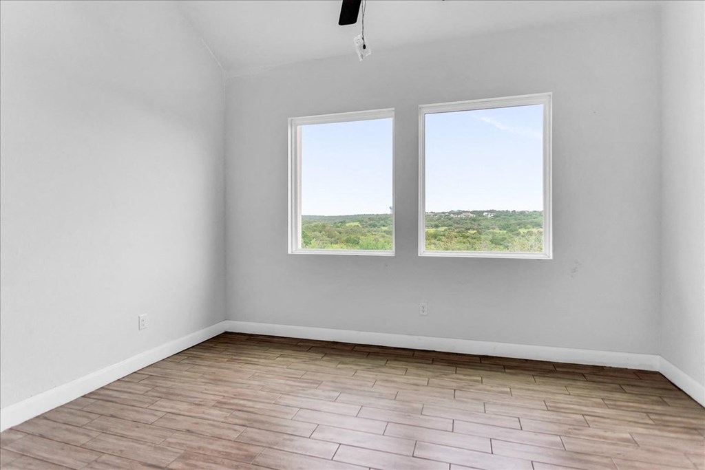 an empty room with two windows and wood floors