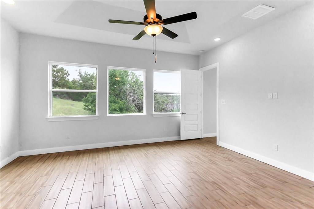 an empty living room with wood floors and a ceiling fan