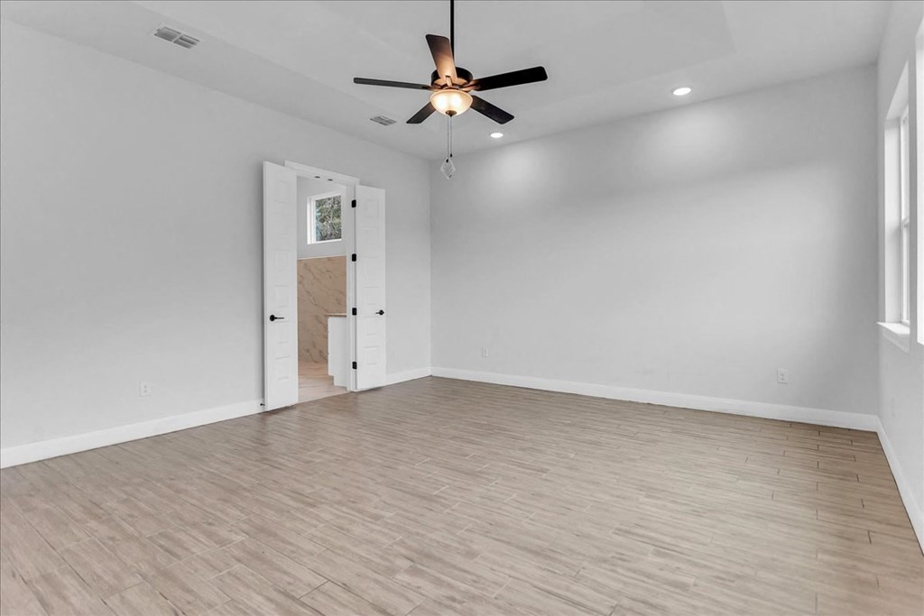 an empty living room with white walls and a ceiling fan