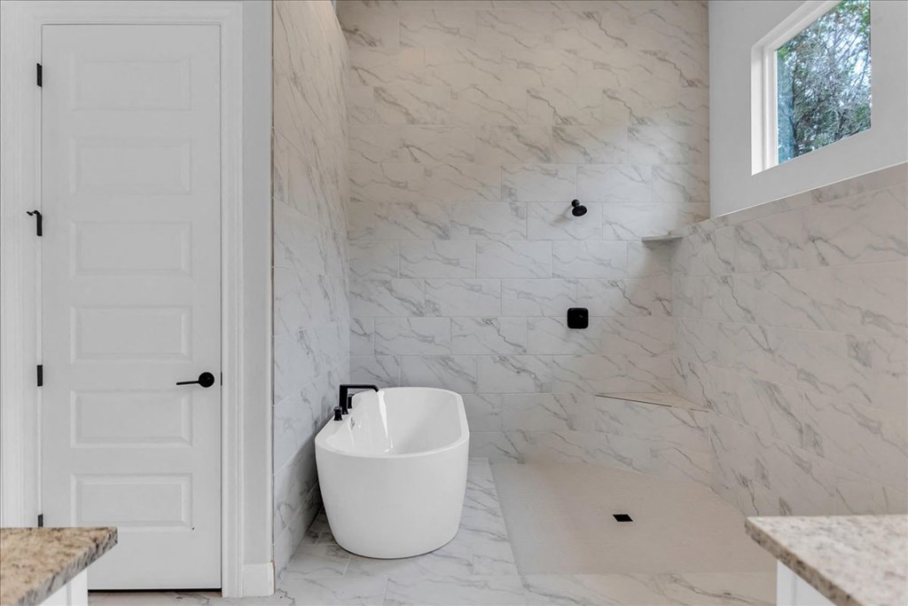 a bathroom with white marble walls and a white tub