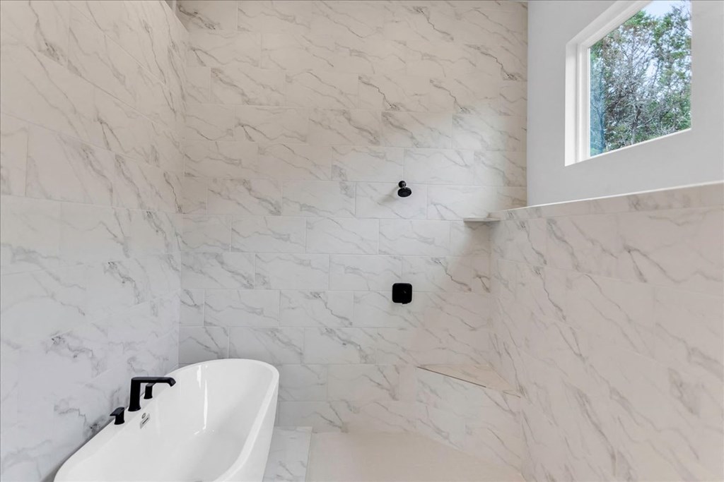 a white marble bathroom with a tub and a window