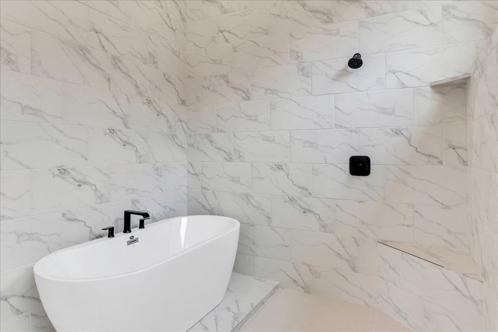 a white bathroom with a white tub and a black wall light
