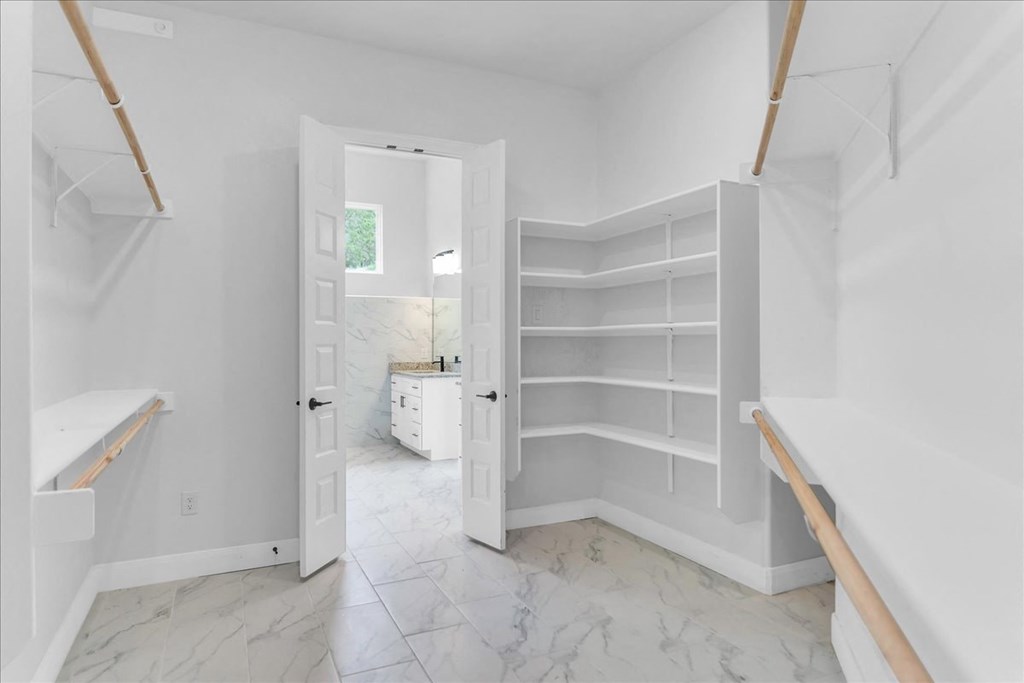 a large white bathroom with white shelves in it