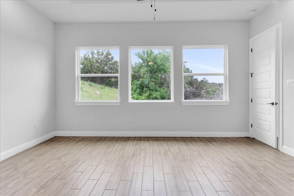 an empty room with three windows and wood floors