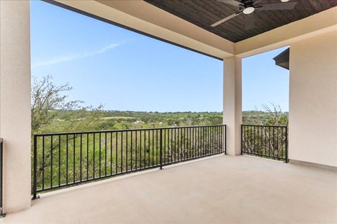 a covered porch with a view of the grass and trees