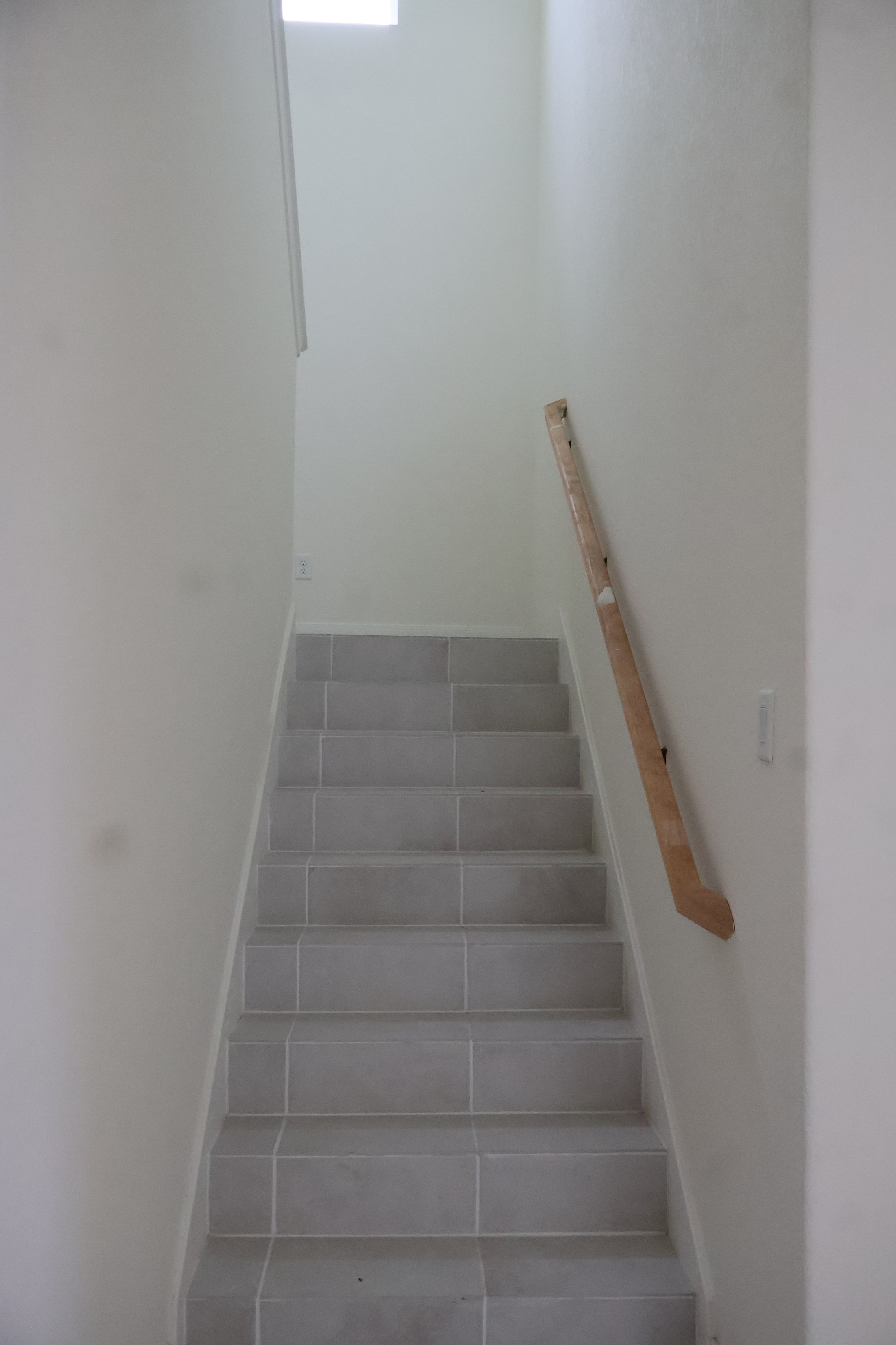 stairs in a white room with a wooden stair railing and a white wall