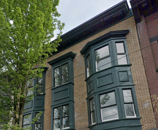 a building with green windows and a tree